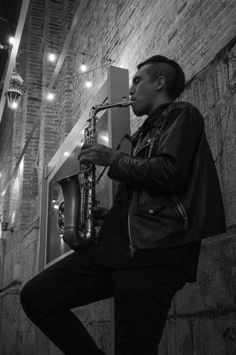 Black and white photo of a saxophonist playing in the street at night in Cuenca, Ecuador.