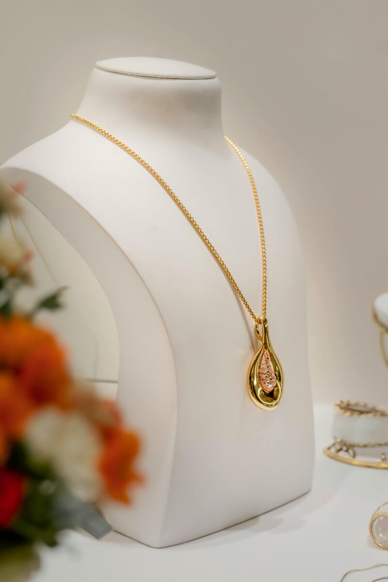 Gold necklace featuring an ornate pendant elegantly displayed on a jewelry stand, symbolizing luxury.