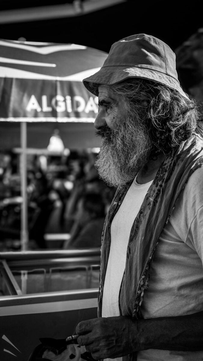 Black and white portrait of an elderly street musician with a beard and hat, captured in Eskişehir, Türkiye.