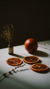 Moody still life of dried orange slices and herbs on a table with artistic light.