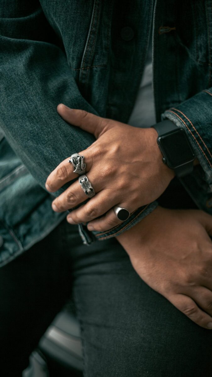 Detailed close-up of hands wearing rings and a smartwatch, showcasing style and technology.